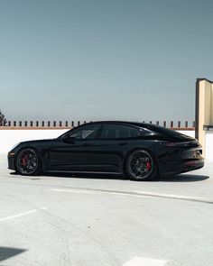 a black sports car parked in front of a building with red rims on it