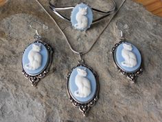 For sale are beautiful cat cameo jewelry sets!!! I have several colors, please do browse my store and message me with your color choice. The cameos are gorgeous, very detailed!!!  They are offered at a reasonable price, make perfect gifts, and are wonderful quality!!!!  The cameos are set in  tibetan silver settings, 1 1/2" long, please see the photos.  The bracelet is silver plated, quite sturdy, adjustable and has a beautiful lace bezel.  The chain is 22" .925 silver plated 1.2mm snake chain, Blue Jewelry With Cat Design For Gift, Blue Cat Design Jewelry For Gift, Blue Cat Design Jewelry As Gift, Vintage Jewelry With Cat Design For Gift, Vintage Silver Cat Design Jewelry, Cameo Pendant Necklace, Goth Accessories, Cameo Earrings, Cameo Jewelry