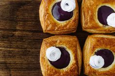 four pastries with cream on them sitting on top of a wooden table