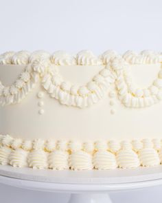 a cake with white frosting and decorative decorations on it's side, sitting on a platter