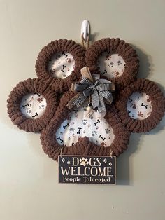 a dog's welcome sign hanging from the side of a wall with paw prints on it