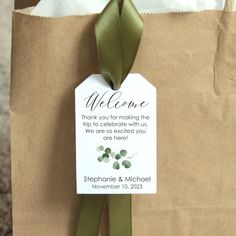 a brown paper bag with a green ribbon tied around it and a welcome tag on the front