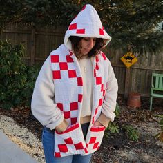 a woman wearing a red and white checkered sweater with a hoodie over her shoulders