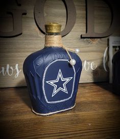 a blue bottle with a white star on it sitting on a wooden table next to a sign