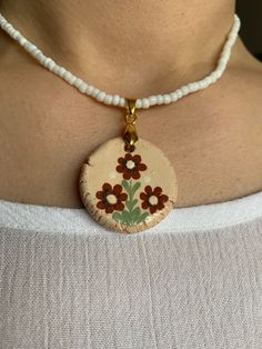 a woman wearing a necklace with flowers painted on it