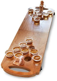 a wooden table topped with lots of bowls and cups filled with liquid on top of it