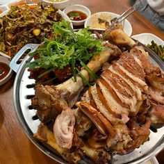 a platter full of meat and vegetables on a table with other dishes in the background