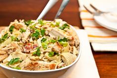 a white bowl filled with food sitting on top of a wooden table next to a fork