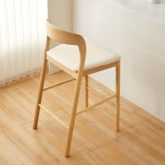 a wooden chair sitting on top of a hard wood floor next to a white wall