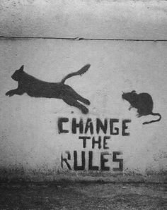 a black and white photo of two cats on a wall with the words change the rules painted on it