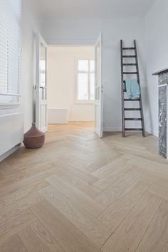 an empty room with white walls and wood flooring is pictured in this image, there is a ladder leaning against the wall