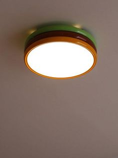 a green and yellow light hanging from the ceiling in a room with no one around it