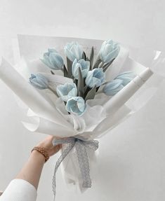 a person holding a bouquet of flowers in their left hand and wrapped in tissue paper