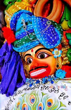 an elaborately decorated mask is displayed in front of other colorful items and decorations on display