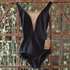 a black swimsuit hanging on a wooden rack in front of some bushes and trees