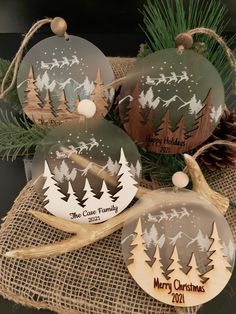 three christmas ornaments on top of a burlock with pine cones and evergreens