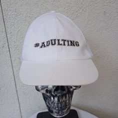 a white hat with the word adulting on it sitting on top of a table