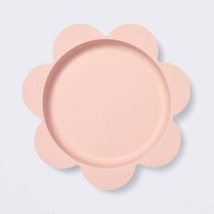 an empty pink plate on a white surface with a flower shaped design in the center