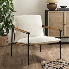 a white chair sitting on top of a wooden floor next to a potted plant