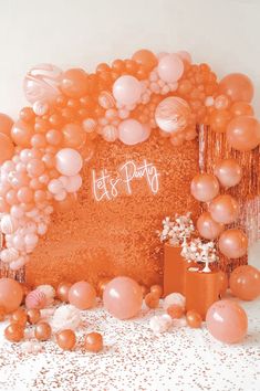 balloons and confetti are scattered around an orange backdrop with the words let's party written on it