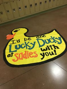 a large yellow ducky sign on the ground in front of lockers that says, i'd be lucky duty at sadie