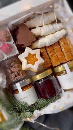 an assortment of cookies, jams and other treats in a gift box on a table