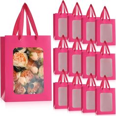 a pink shopping bag next to a bunch of small bags with flowers in them on display