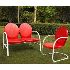 two red chairs sitting on top of a lush green field