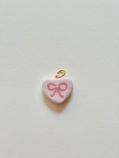 a small pink heart shaped object with a bow on it's end, against a white background