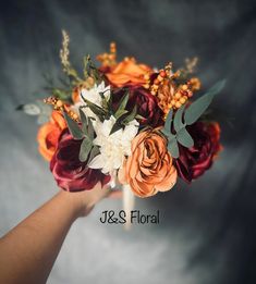 a hand holding a bouquet of flowers on top of a gray background with the words j & s floral