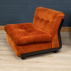 an orange chair sitting on top of a hard wood floor