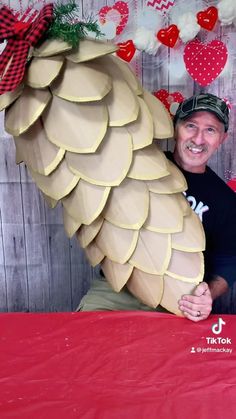 a man sitting in front of a giant paper mache palm tree with hearts on it