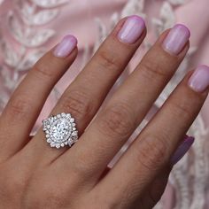 a close up of a person's hand with a diamond ring on her finger