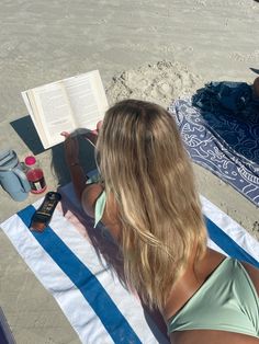 a woman reading a book on the beach