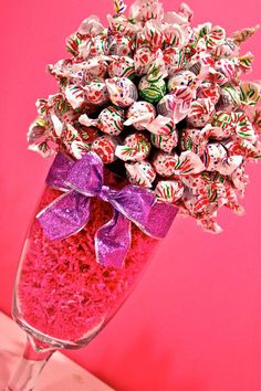 a vase filled with candy and candies on top of a pink table next to a wall