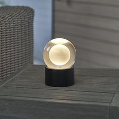 a glass ball sitting on top of a wooden table next to a wicker chair