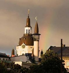 a rainbow is seen in the sky over a building with steeple and spires