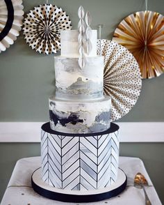 a three tiered cake sitting on top of a table next to decorative paper fans