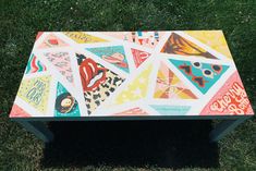 a colorful bench sitting in the grass on top of green grass with lots of stickers