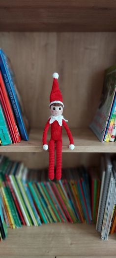 an elf doll is sitting on a book shelf in front of many children's books