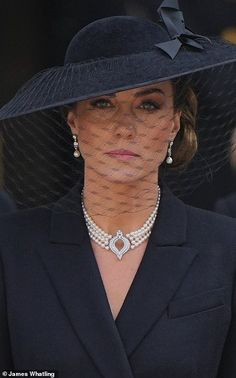 a woman wearing a black hat with a veil over it's brim and diamond necklace