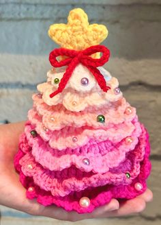 a small crocheted christmas tree is shown in pink, yellow and red colors