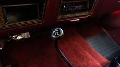 the interior of an old car with red carpet and black dash board, including two radio's