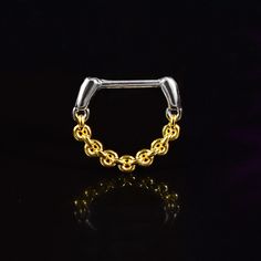 a gold and silver chain ring on a black background with reflection in the foreground