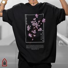 Introducing our "Clothed with Majesty" graphic tee, inspired by Psalm 104 and Japanese Streetwear. This Christian streetwear t-shirt features a striking vertical inscription on the front, with the word "Honor" and a graphic of a delicate pink Japanese Cherry Blossom branch.  On the back of the shirt, you'll find the powerful scripture from Psalm 104:1-9, "Bless Yahweh, my soul. Yahweh, my God, you are very great. You are clothed with honor and majesty." The scripture is accompanied by a stunning image of a large pink Japanese Cherry Blossom branch, adding a unique and meaningful touch to the tee. Available in 14 colors and 7 sizes, our graphic tee is perfect for both men and women. It serves as a beautiful expression of faith and a reminder of the majesty of our Creator. Whether you're loo