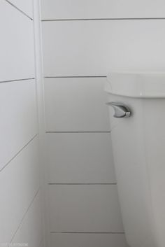 a white toilet sitting in a bathroom next to a wooden wall with planks on it