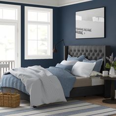 a bedroom painted in blue and white with a bed, nightstands, window, rug and basket