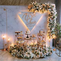 a table topped with cakes and cupcakes next to a wall covered in flowers