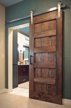 an open wooden door in the middle of a room with green walls and carpeting