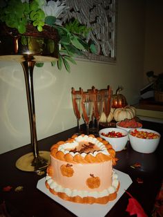 there is a cake on the table with other desserts in bowls and glasses behind it